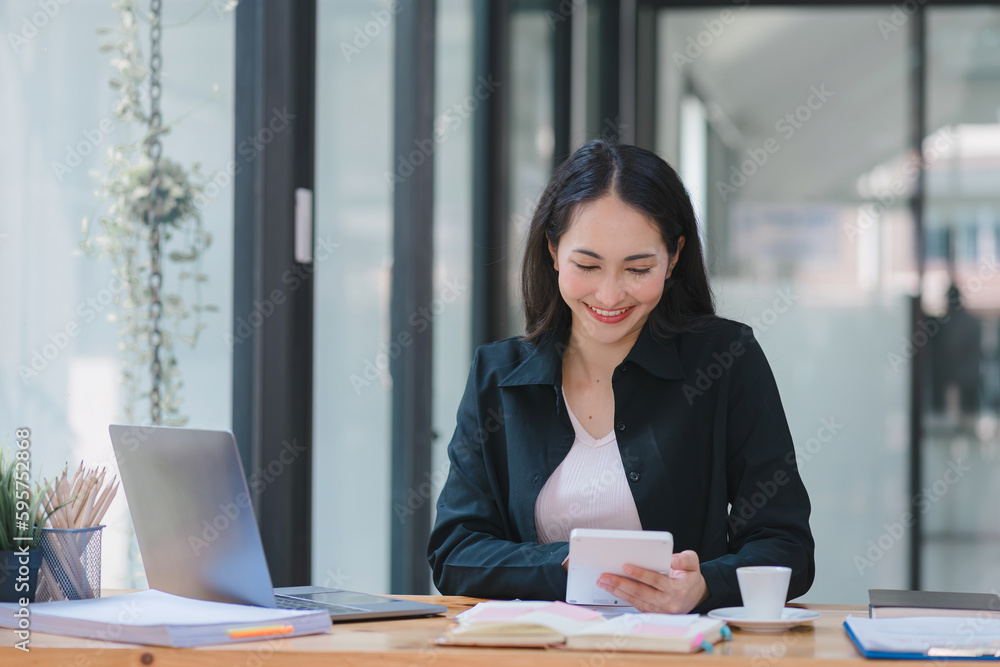 A businesswoman is working at her desk, using a calculator to perform calculations. Finance and accounting concept. A businesswoman is working at her desk, using a calculator to perform calculations. Finance and accounting concept.