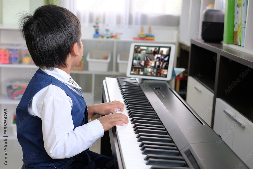 Young pianist boy looking at the digital tablet screen for learning piano  online at home. Music distance learning concept. Stock Photo | Adobe Stock