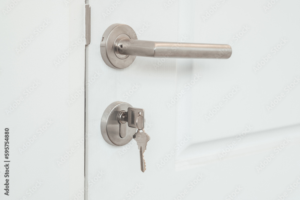 Key in a keyhole at the white door. House door with metal keys. Key in a keyhole at the white door. House door with metal keys.
