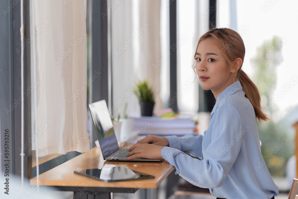 happy young businesswoman Asian siting on the chairs cheerful demeanor raise holding coffee cup smiling looking laptop screen .Making opportunities female working successful in the office. happy young businesswoman Asian siting on the chairs cheerful demeanor raise holding coffee cup smiling looking laptop screen .Making opportunities female working successful in the office.