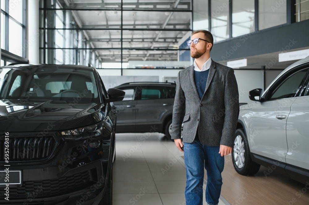 A man walks around a car dealership and chooses a new car. A man walks around a car dealership and chooses a new car.