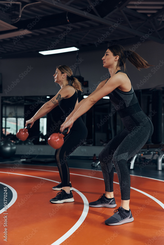 Sporty women doing russian kettlebell exercise in a gym.