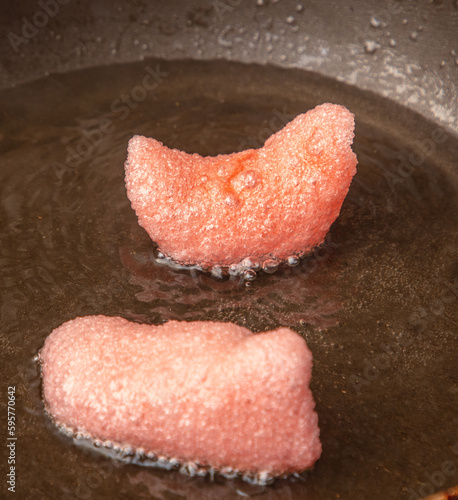 Red chips are fried in oil in a frying pan