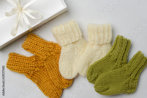 Small baby socks, made of cotton yarn, on white wooden background