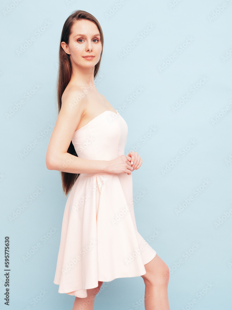 Portrait of young winsome woman in romantic attire pretty smiling on blue background. Slim female in pure pink dress posing in studio. Cheerful model. Isolated. Long hair Portrait of young winsome woman in romantic attire pretty smiling on blue background. Slim female in pure pink dress posing in studio. Cheerful model. Isolated. Long hair