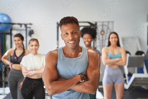 Confident sporty man posing in front of a group of people in the gym. Sports concept.