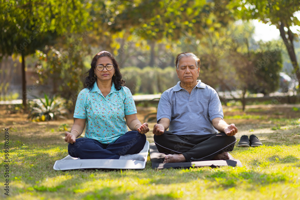 Mature couple meditating in public park Mature couple meditating in public park