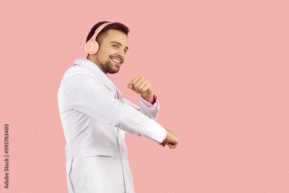 Overjoyed young man in suit isolated on pink studio background wear wireless headphones listen to music. Smiling guy in earphones enjoy good quality sound in modern device. Technology. Overjoyed young man in suit isolated on pink studio background wear wireless headphones listen to music. Smiling guy in earphones enjoy good quality sound in modern device. Technology.