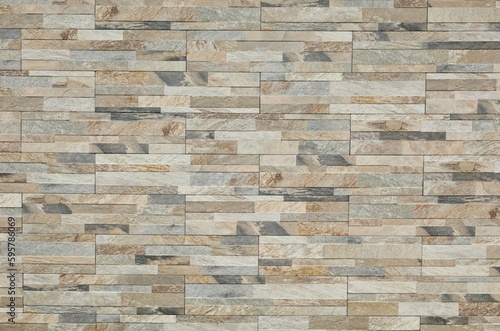 Stoneware paneling wall with stone effect. Colors are shade of gray ,brown and white. Exterior home decor, background and texture.