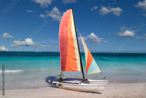 Colorful sailing catamaran on the beach of the Varadero - Cuba. Turquoise blue Atlantic water and blue sky with white clouds.