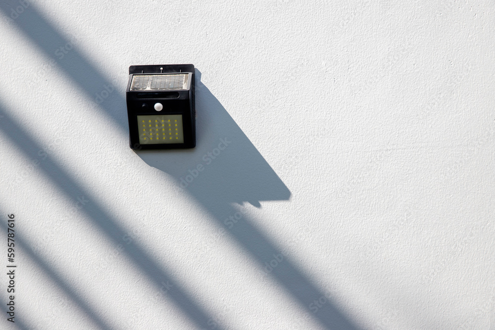 Fototapeta premium Solar-powered motion sensor light isolated on cement or concrete wall background, selective focus.