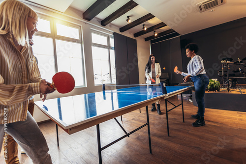 Young people playing table tennis in the office at work