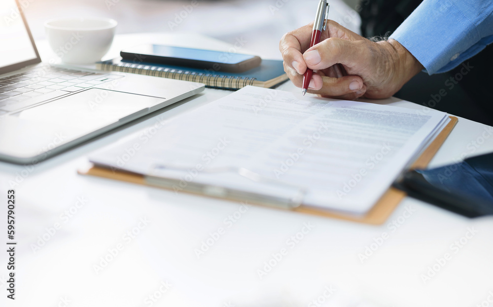 Asian businessman reviewing document reports at office workplace with computer laptop. legal expert, professional lawyer reading and checking financial documents or insurance contract Asian businessman reviewing document reports at office workplace with computer laptop. legal expert, professional lawyer reading and checking financial documents or insurance contract