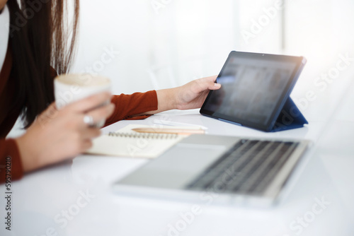 Asian teenage woman study online class at home or cafe by using tablet and laptop, video call with teacher and friends learning, university student studying online concept