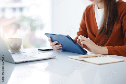 Asian teenage woman study online class at home or cafe by using tablet and laptop, video call with teacher and friends learning, university student studying online concept