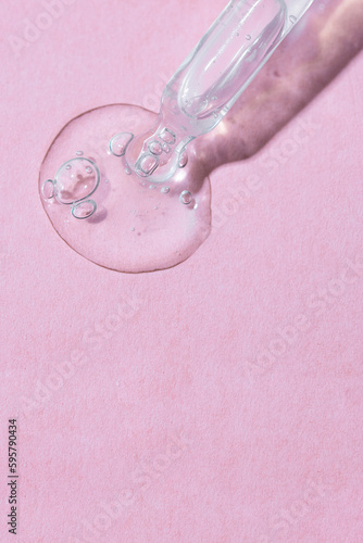 Abstract Pipette dropper with transparent liquid drops on pink background. Concept for Laboratory investigation, medicine, science research, cosmetic and perfume industry