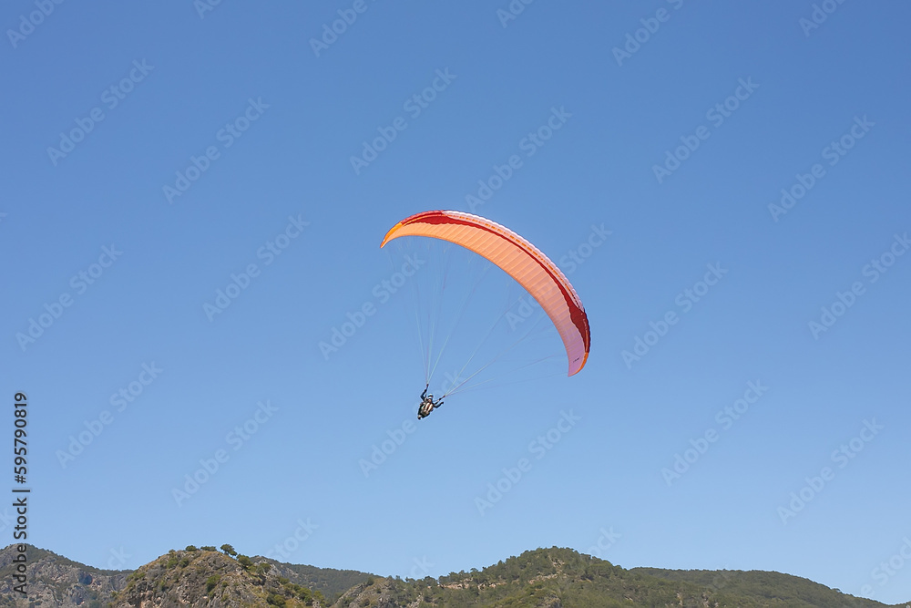 Paraglider in the blue sky. The sportsman flying on a paraglider. Paraglider in the blue sky. The sportsman flying on a paraglider.