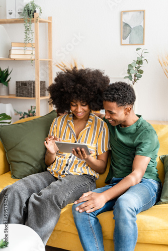 Black couple using tablet on sofa