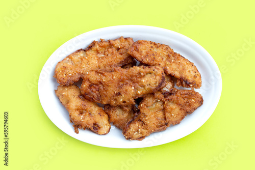 Fried bananas in white plate on blue green background.