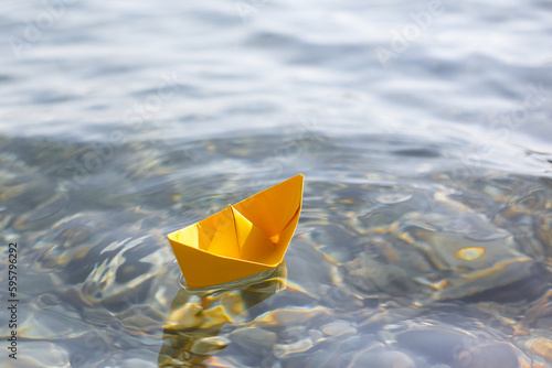 Yelow paper boat sailing on blue water surface photo