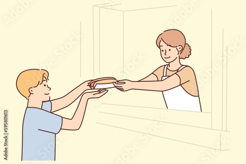 Man buys fresh hot dog, wanting to dine on fast food and satisfy hunger while walking