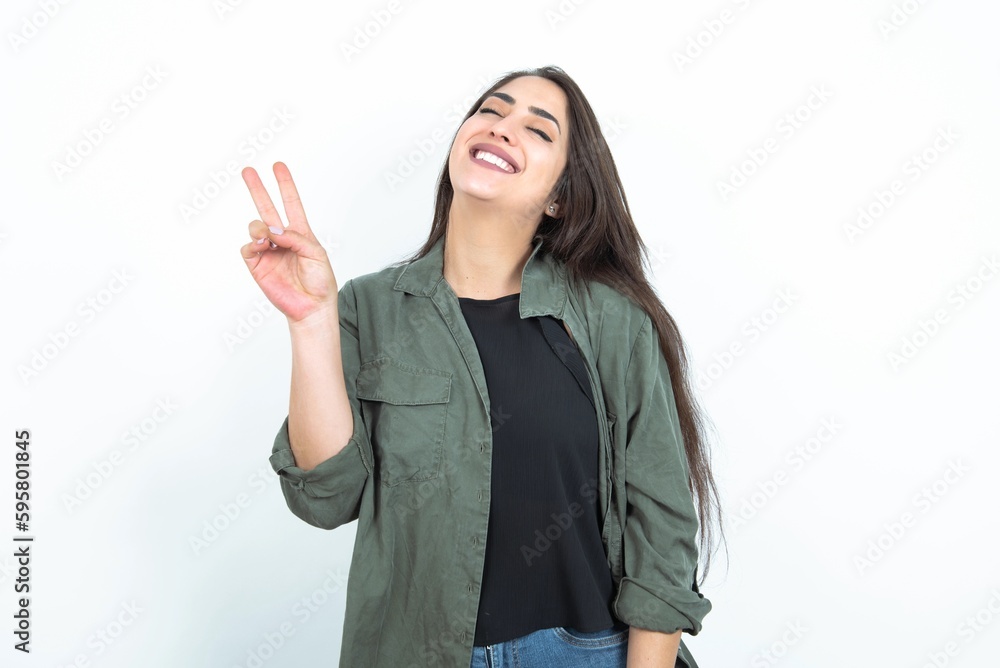 young brunette woman wearing casual clothes over white studio background smiling with happy face winking at the camera doing victory sign. Number two. young brunette woman wearing casual clothes over white studio background smiling with happy face winking at the camera doing victory sign. Number two.