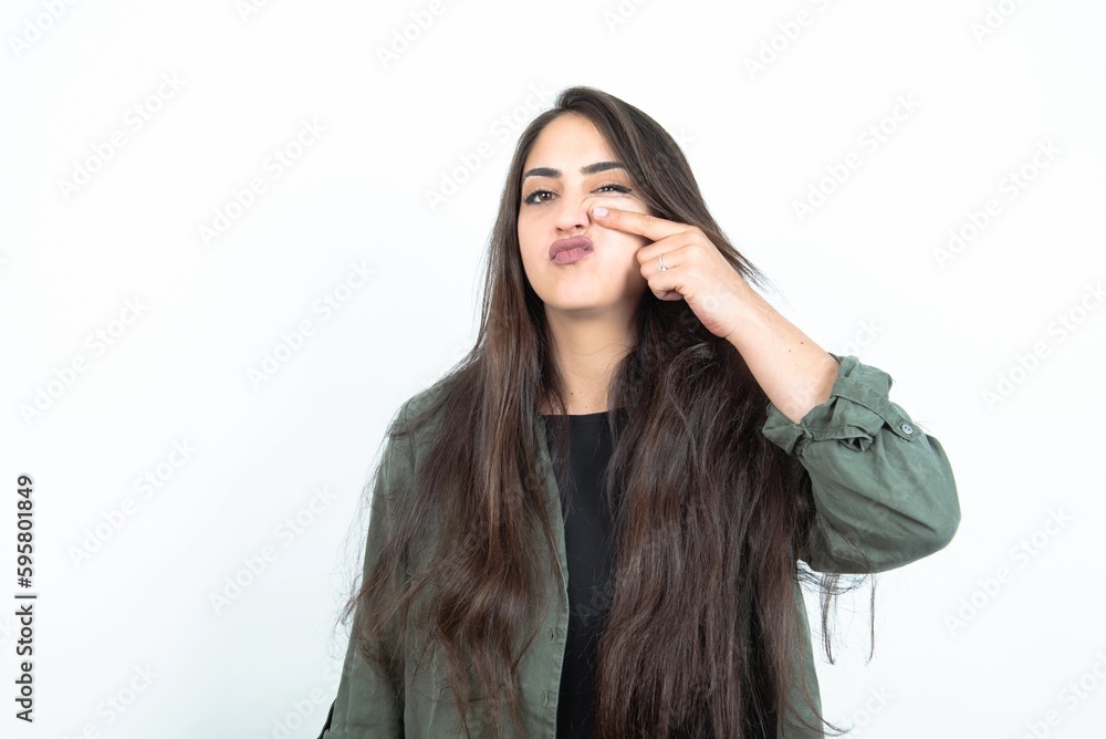 young brunette woman wearing casual clothes over white studio background pointing unhappy to pimple on forehead, ugly infection of blackhead. Acne and skin problem young brunette woman wearing casual clothes over white studio background pointing unhappy to pimple on forehead, ugly infection of blackhead. Acne and skin problem