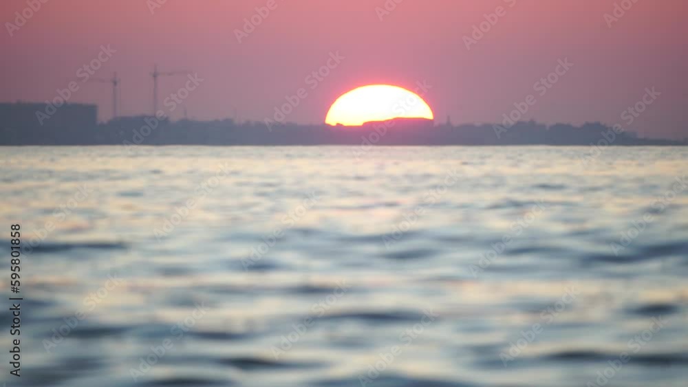 Sunset sea and silhouette of resort town located on the seashore with red sunset sun behind. Holiday recreation concept. Abstract nautical summer ocean sunset nature background. Sunset sea and silhouette of resort town located on the seashore with red sunset sun behind. Holiday recreation concept. Abstract nautical summer ocean sunset nature background.