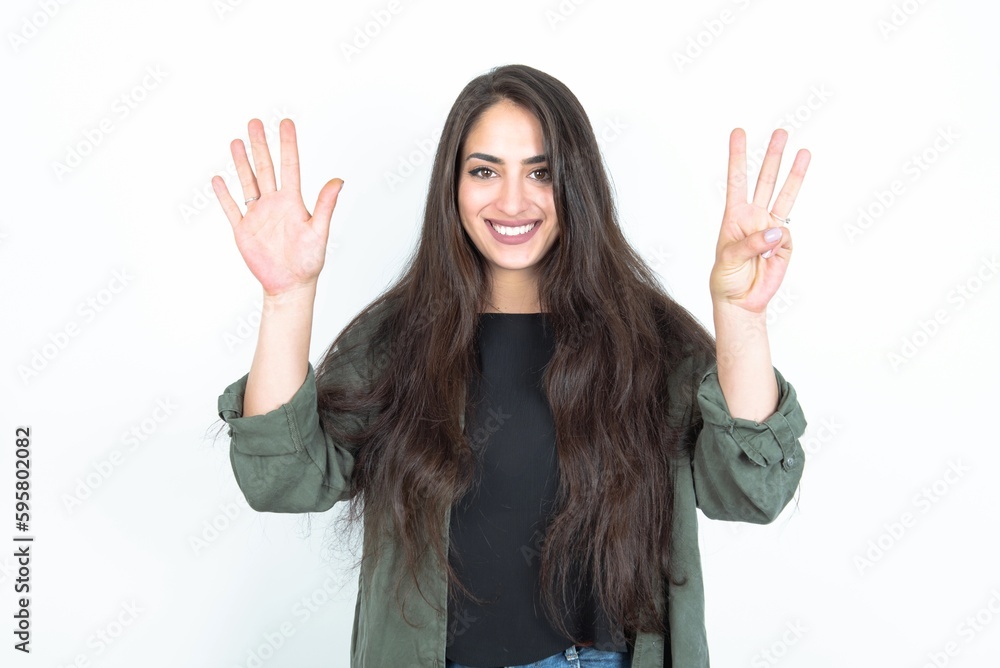 young brunette woman wearing casual clothes over white studio background showing and pointing up with fingers number eight while smiling confident and happy. young brunette woman wearing casual clothes over white studio background showing and pointing up with fingers number eight while smiling confident and happy.