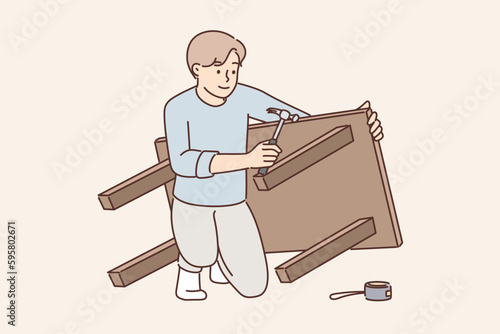Man assembles table after buying it in furniture store and repairs DIY wooden desk for kitchen