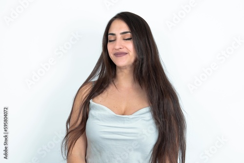 young brunette woman wearing white tank top over white studio background nice-looking sweet charming cute attractive lovely winsome sweet peaceful closed eyes