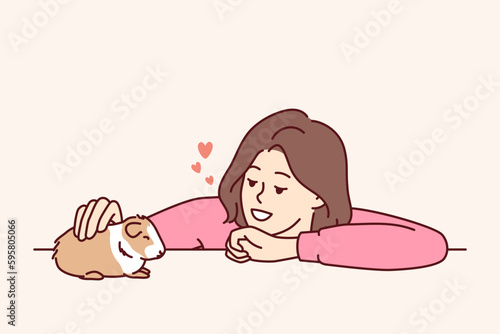 Caring woman pets guinea pig or hamster enjoying companionship of cute pet given to by parents or boyfriend. Young kind girl takes care of guinea pig doing grooming and admiring friendly pet