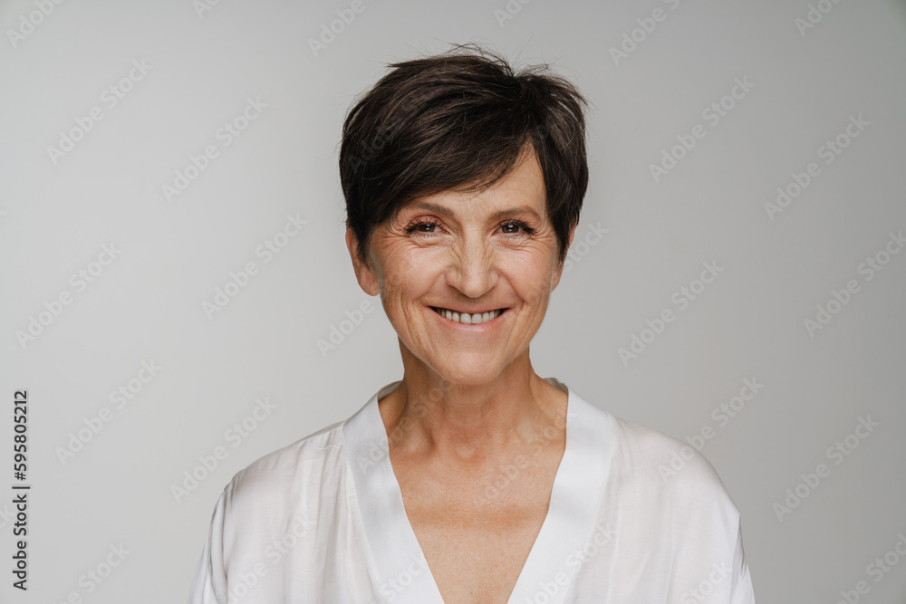Senior woman smiling at camera while standing isolated over white background Senior woman smiling at camera while standing isolated over white background