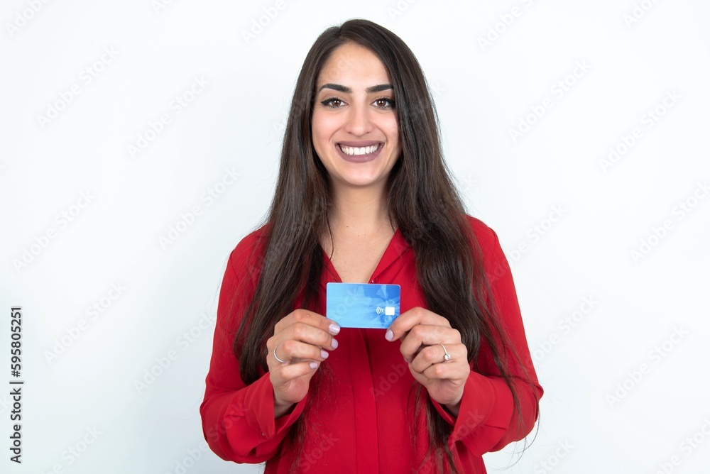 Photo of Young brunette woman wearing red shirt over white studio background positive smile hold credit card income salary Photo of Young brunette woman wearing red shirt over white studio background positive smile hold credit card income salary
