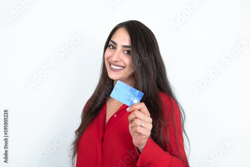 Close up photo of optimistic Young brunette woman wearing red shirt over white studio background hold card