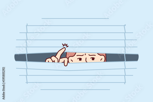 Suspicious man looks out window suffering from schizophrenia and experiencing desire-inducing spy phobia. Eyes of guy looking through venetian blinds to spy on colleagues or passers-by