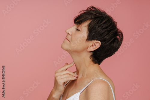 Profile of senior woman posing isolated over pink background