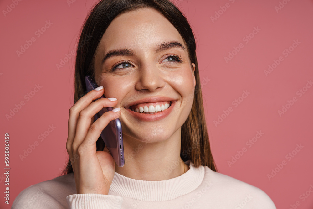 Cheerful woman talking on mobile phone isolated over pink studio background Cheerful woman talking on mobile phone isolated over pink studio background