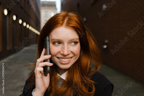 Portrait of beautiful woman smiling while talking on mobile phone outdoors