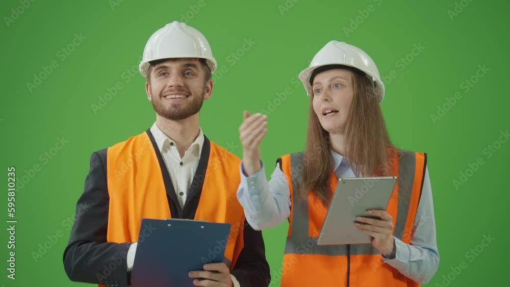 Green Screen.Young Male and Female Civil Engineers in Safety Jackets,White Helmets with Tablet and Paper Clipboard, Discussing Project Work with Interest. Team Work Concept.Modern Construction Concept Green Screen.Young Male and Female Civil Engineers in Safety Jackets,White Helmets with Tablet and Paper Clipboard, Discussing Project Work with Interest. Team Work Concept.Modern Construction Concept