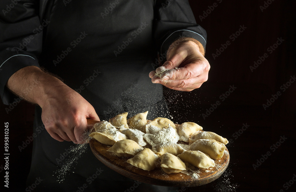 Professional chef throws flour to raw dumplings on a cutting kitchen board before cooking. Black space for menu or recipe