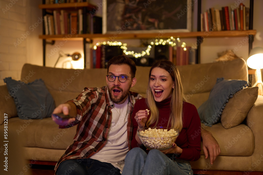 Young romantic couple watching TV at home