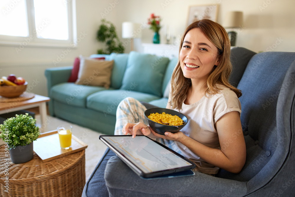 Smiling woman with digital tablet and breakfast at home