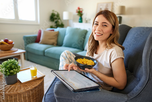 Smiling woman with digital tablet and breakfast at home