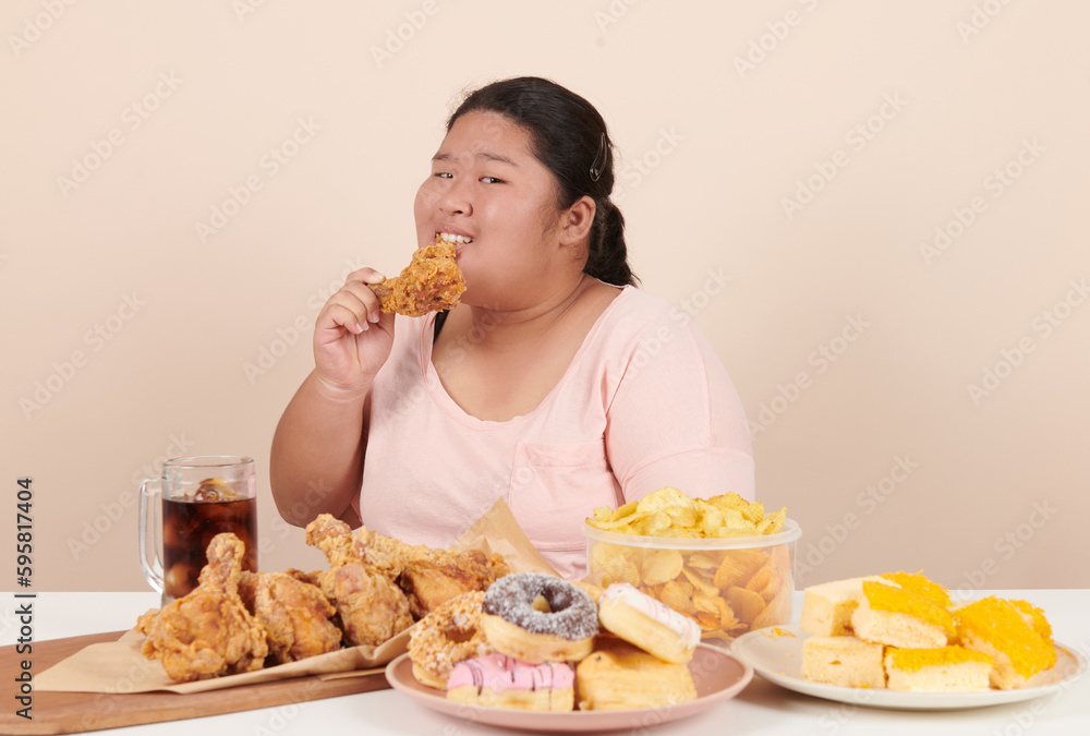 obesity young women binge eating disorder concept with woman eating fast food burger, fired chicken , donuts and desserts, junk food, high calorie foods, overweight female have unhealthy lifestyle. obesity young women binge eating disorder concept with woman eating fast food burger, fired chicken , donuts and desserts, junk food, high calorie foods, overweight female have unhealthy lifestyle.