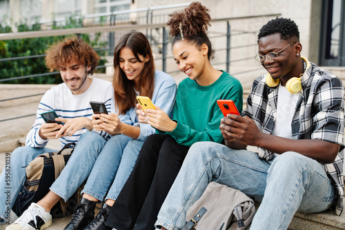 University Students sitting in stairway typing on smartphones - Multicultural group of friends using cellphones  © EFStock