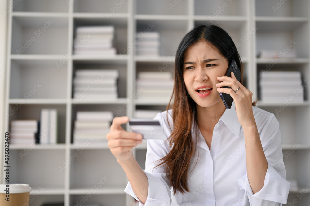 Dissatisfied Asian female office employee contacts a credit card call-center service Dissatisfied Asian female office employee contacts a credit card call-center service