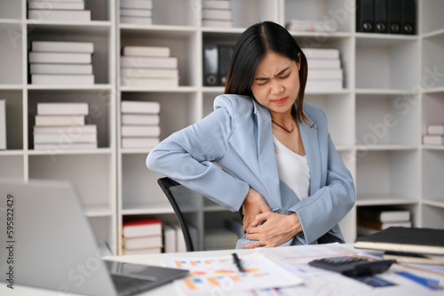 Tired Asian businesswoman suffering from her office syndrome, feeling back pain © bongkarn