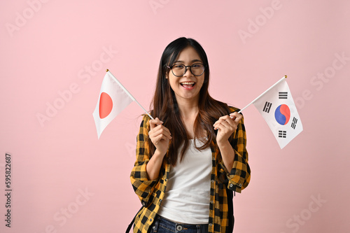Pretty Asian female college student holding the flags of Japan and Korea. Exchange student photo