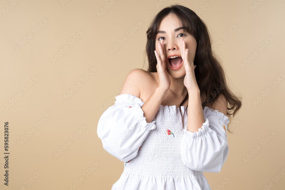 Young Asian woman doing a shocked surprise gesture shouting with hands cupped around mouth isolated brown color background Young Asian woman doing a shocked surprise gesture shouting with hands cupped around mouth isolated brown color background